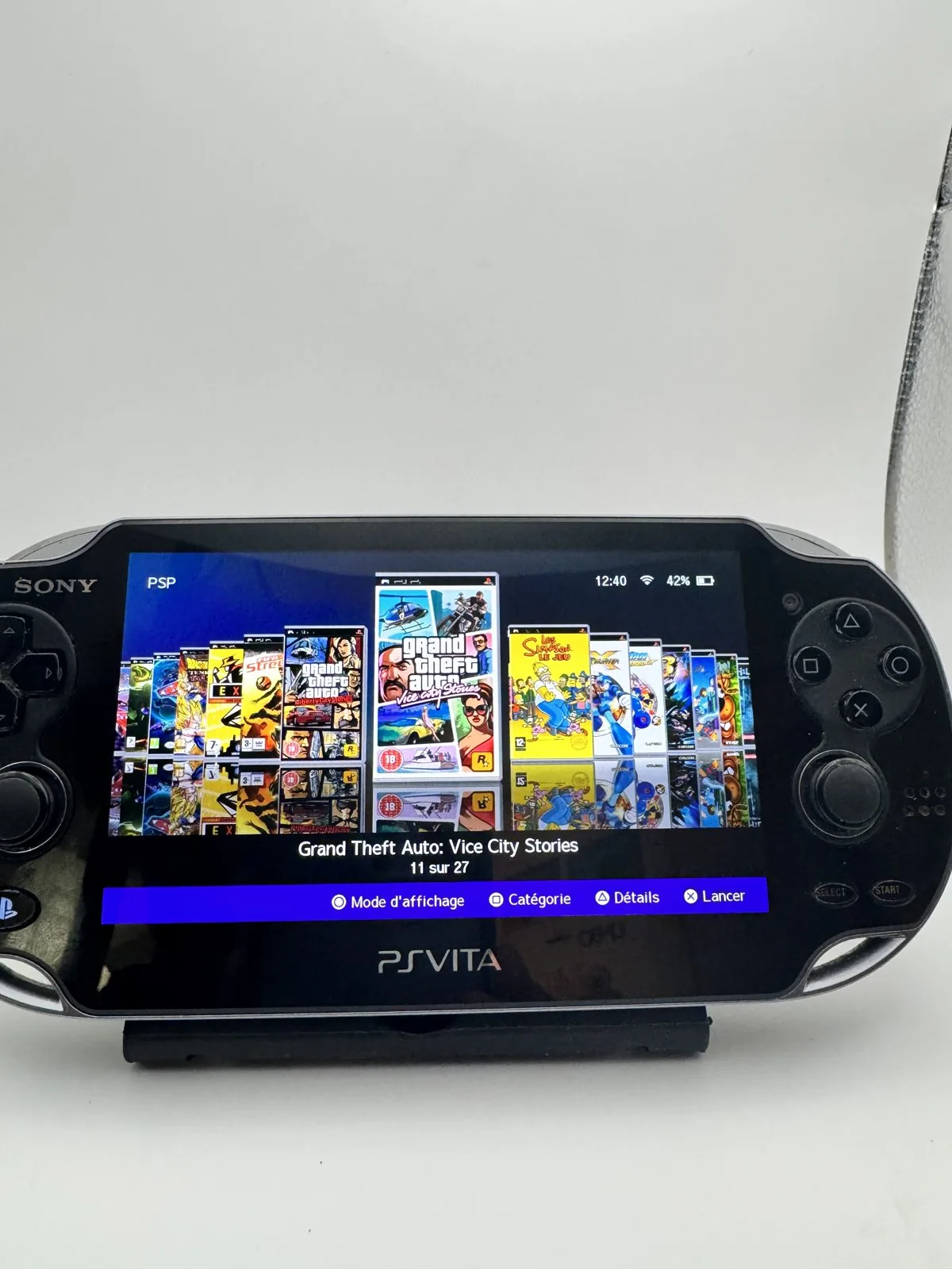 PS Vita OLED remise en état, écran allumé, posée sur l'établi de l'atelier